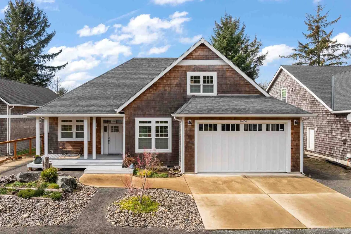 A charming exterior shot of the home's wooden front porch, stone pathway, landscaped garden, and garage door. The setting is both inviting and practical, hinting at easy access to the outdoors for dog walks and neighborhood strolls.