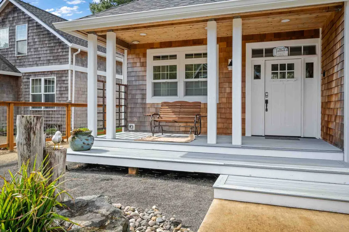 A cozy front porch with a wooden bench and decorative planter, offering a welcoming entrance to the property. The setting exudes warmth and invites guests to linger, whether greeting friends or enjoying a quiet morning alone.
