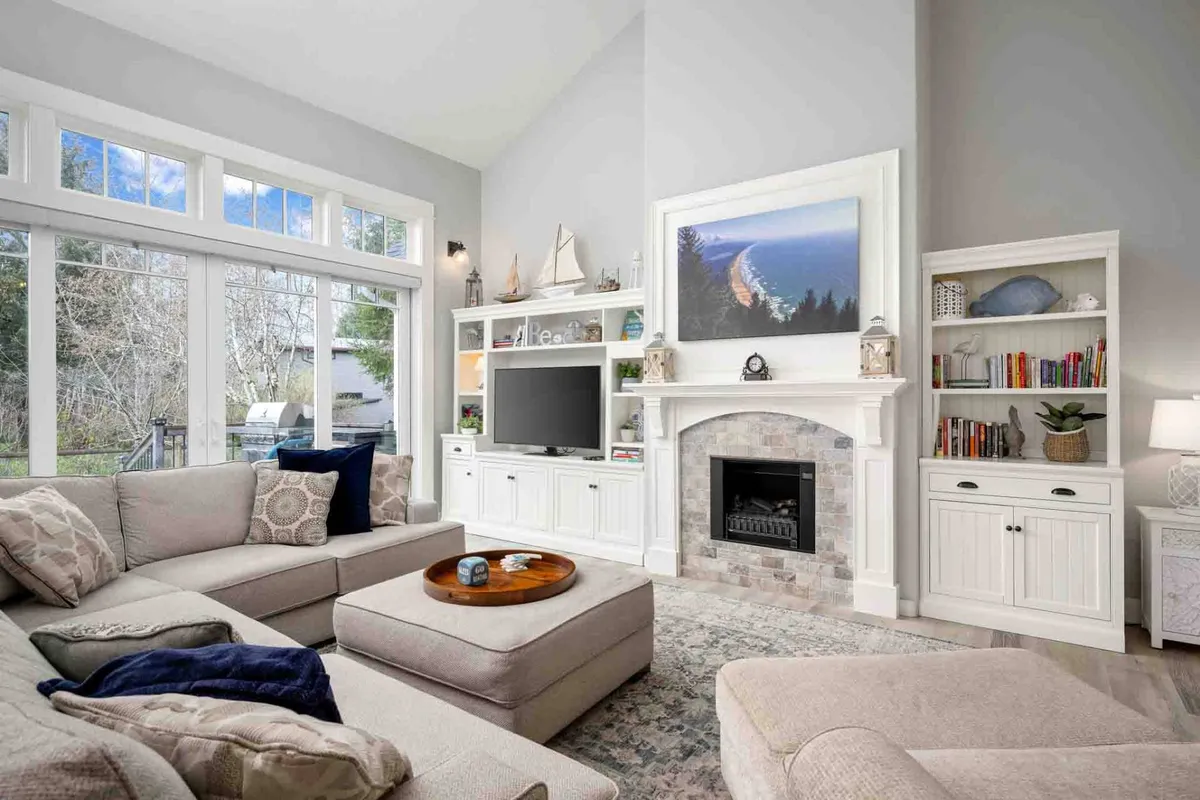 A cozy, comfortable living area featuring a large sectional sofa, a fireplace, big windows, and artwork on the wall. The scene is set for group activities like game nights, movie marathons, or intimate conversations, all in a space that feels both stylish and inviting.